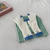 White gloves with blue cuffs on a green and white striped towel, with a box in the background.