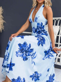 Woman wearing a blue floral dress sitting on a chair against a dark wall.