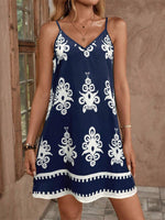 Navy blue dress with white patterns worn by a person, standing against a neutral background.