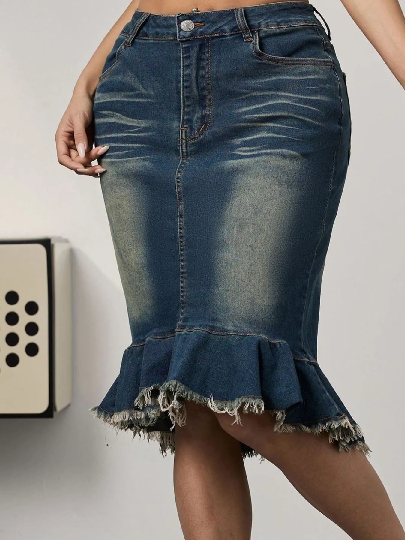Blue denim skirt with ruffled hem on a plain background