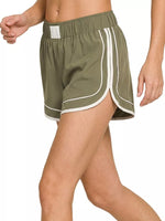 Green athletic shorts with white stripes on a white background