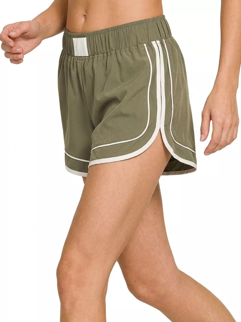 Green athletic shorts with white stripes on a white background