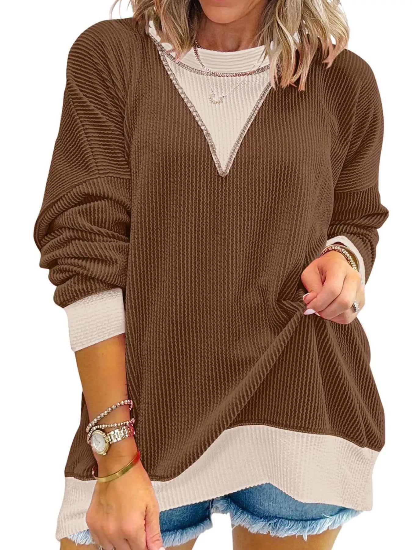 Brown sweater with white trim worn by a person on a white background