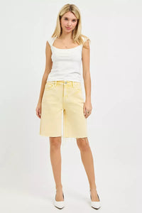Woman wearing a white tank top and yellow shorts on a white background