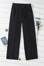 Black pants on a textured white background with a brand tag visible.