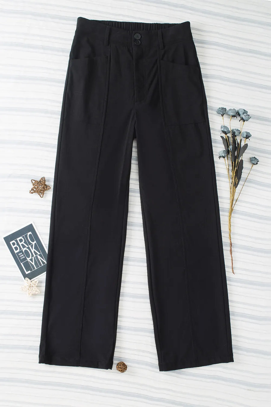 Black pants on a textured white background with a brand tag visible.
