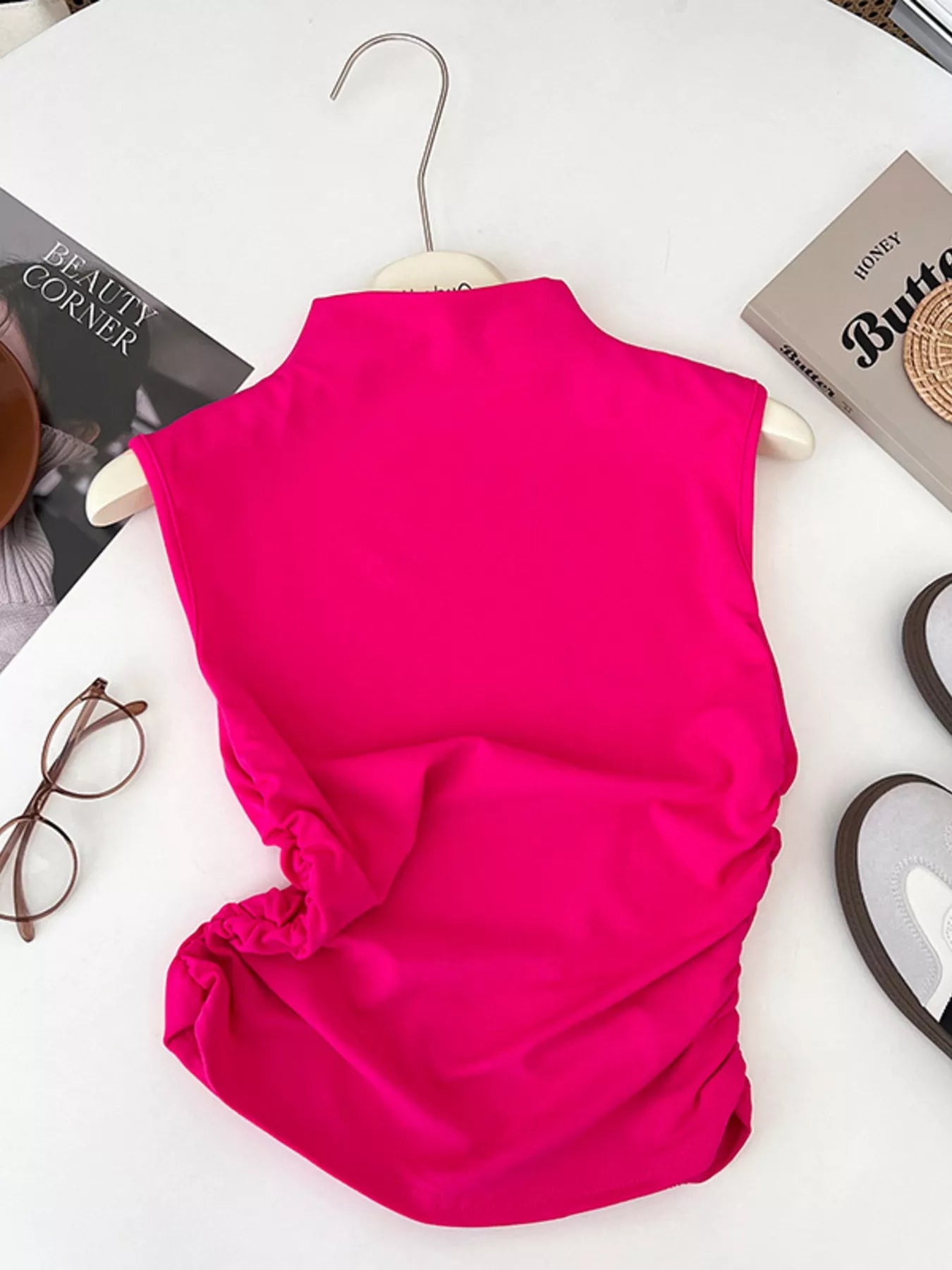 Pink sleeveless top on a hanger with a white background