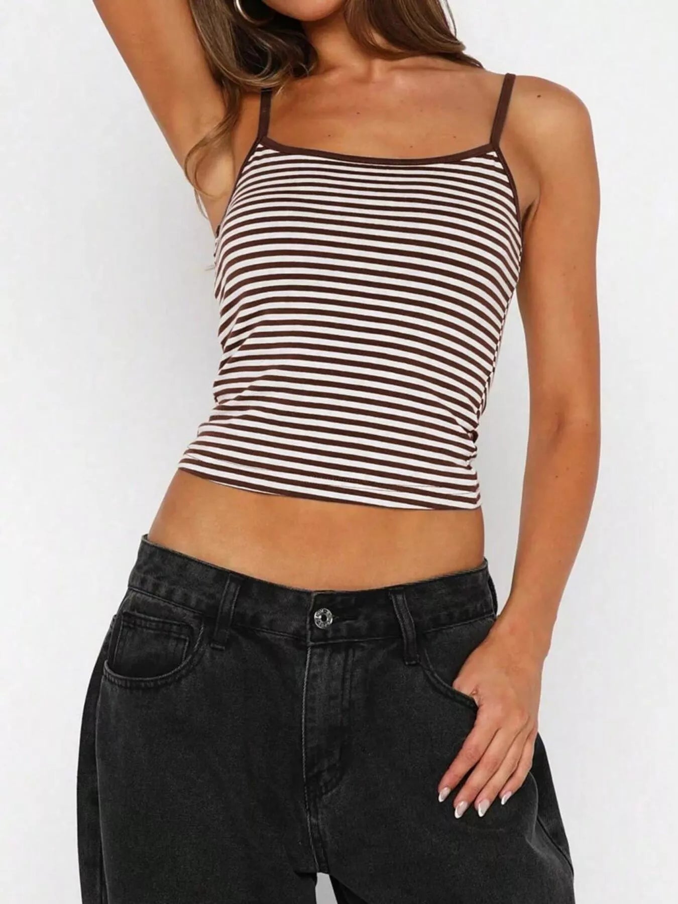 Woman wearing a black and white striped tank top and black jeans on a white background