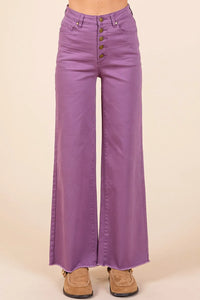 Purple flared jeans with button details on a beige background