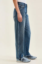 Person wearing blue jeans and sneakers on a plain background