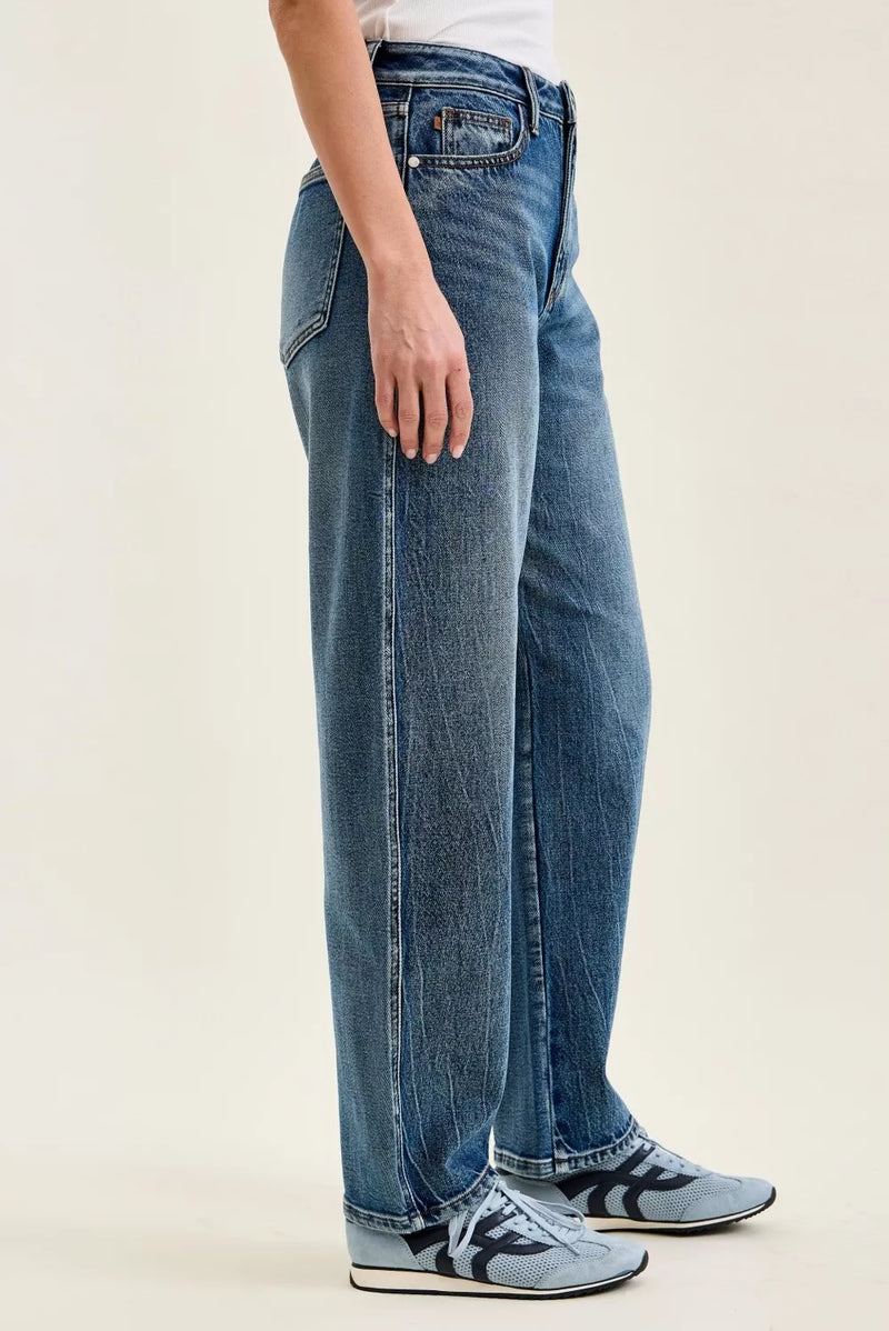 Person wearing blue jeans and sneakers on a plain background