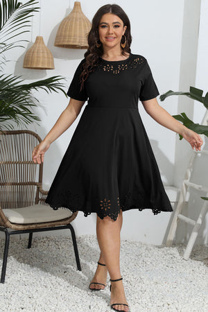 Woman wearing a black dress with lace details in an indoor setting.