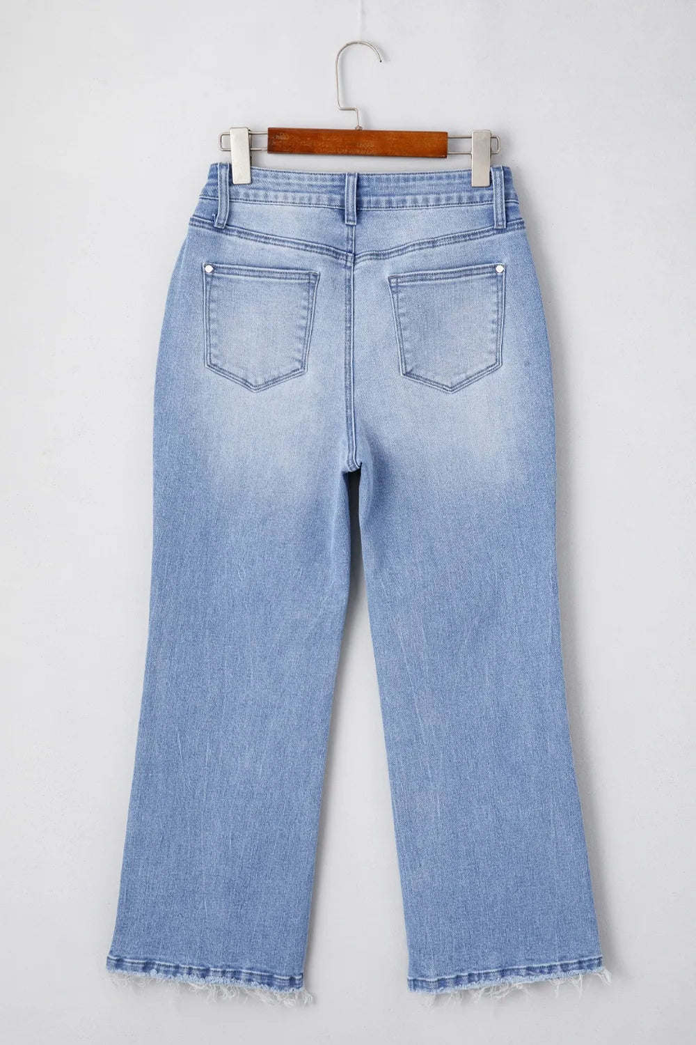 Light blue jeans on a hanger against a white background