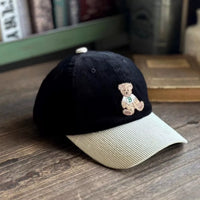 Black cap with a teddy bear emblem on a wooden surface