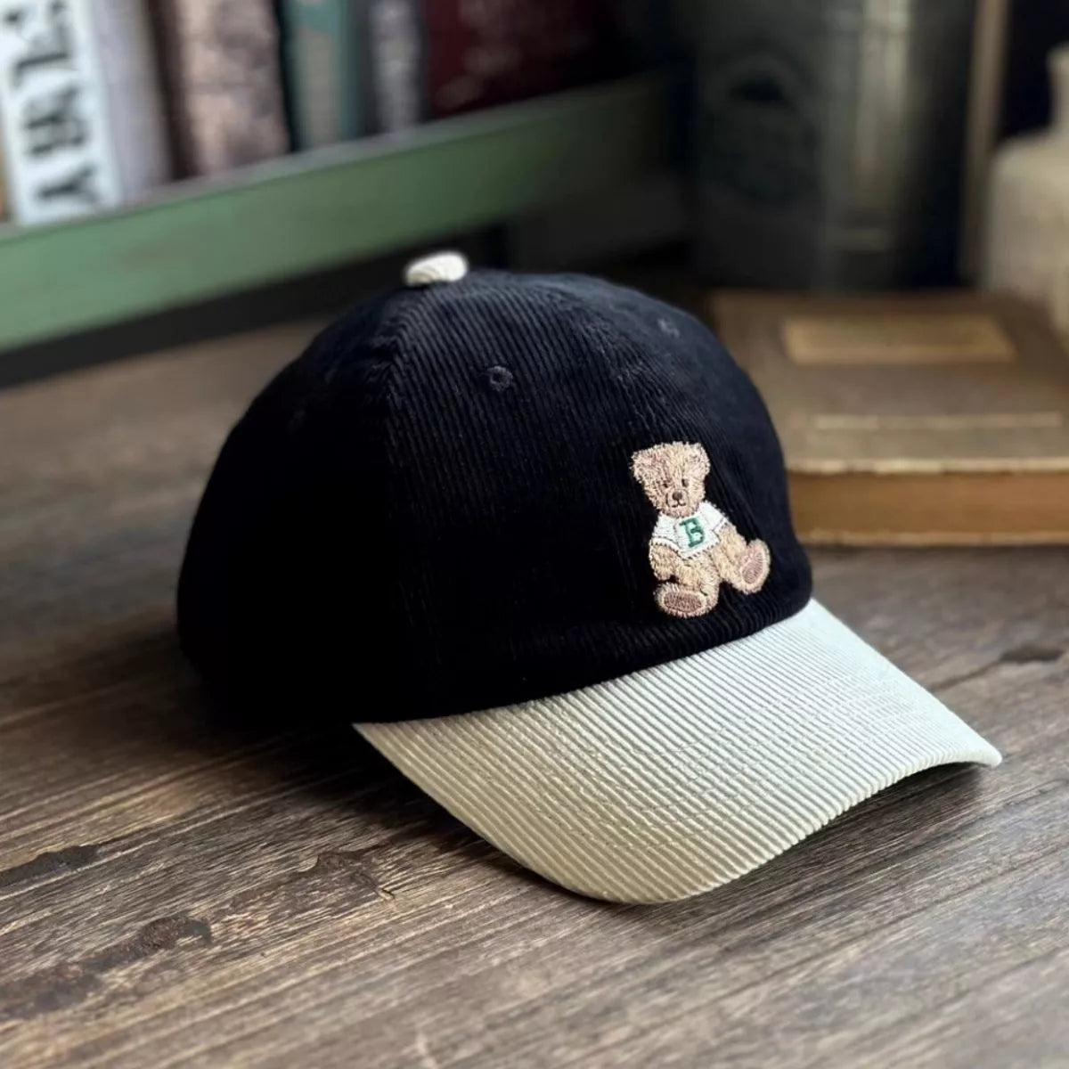 Black cap with a teddy bear emblem on a wooden surface