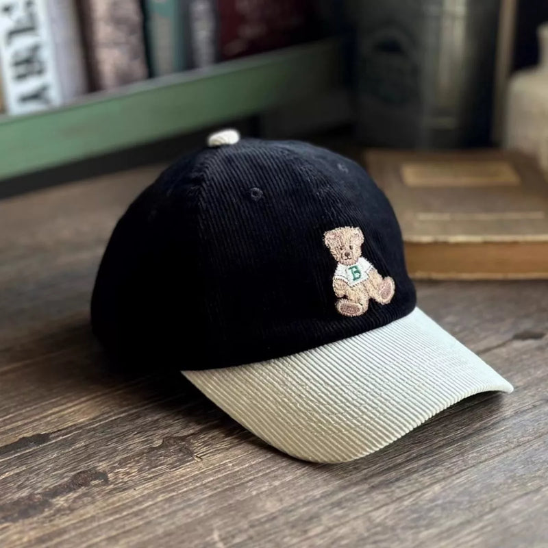 Black cap with a teddy bear emblem on a wooden surface