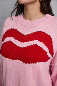 Pink sweater with red lips design worn by a person