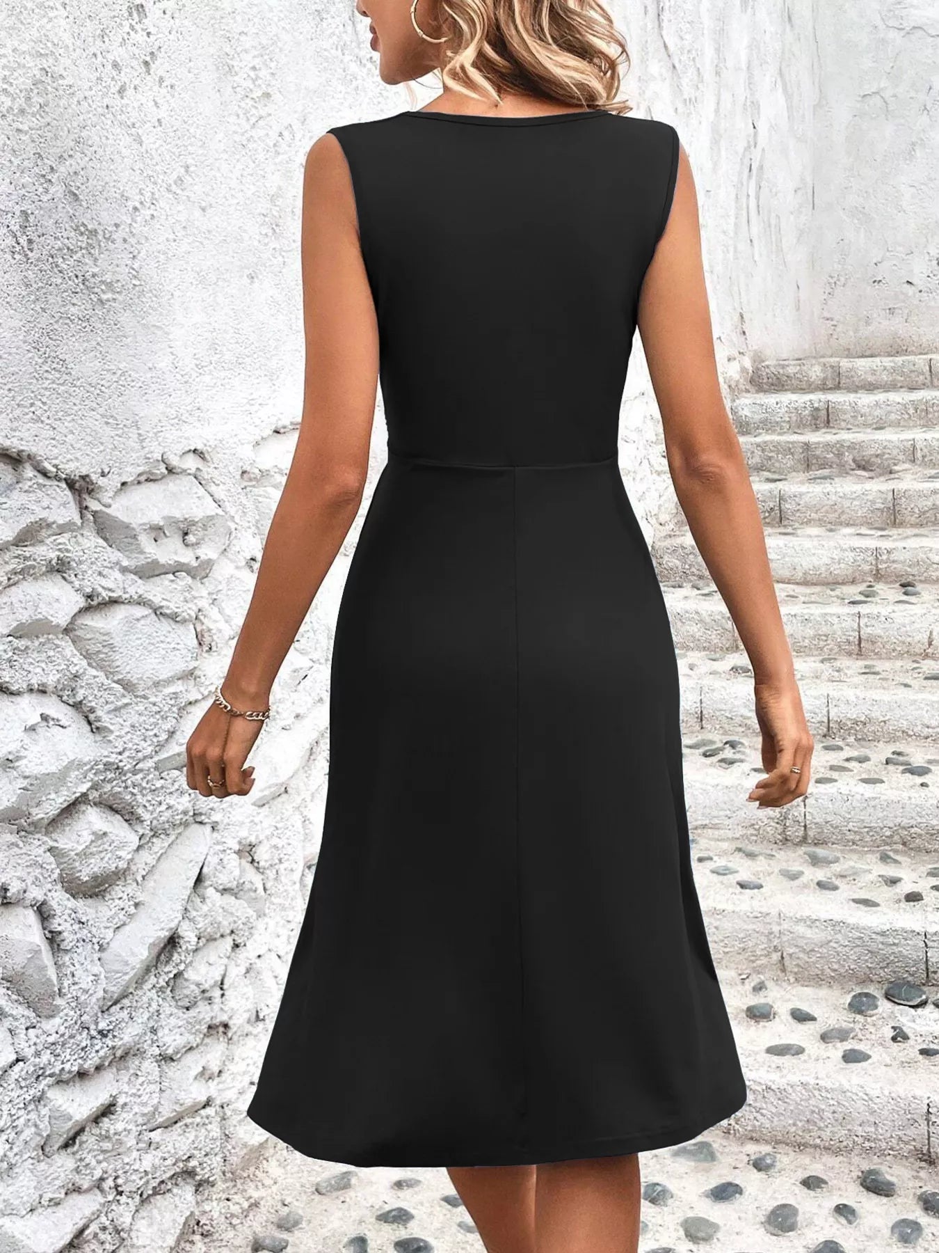 Woman wearing a black dress standing on a stone staircase.