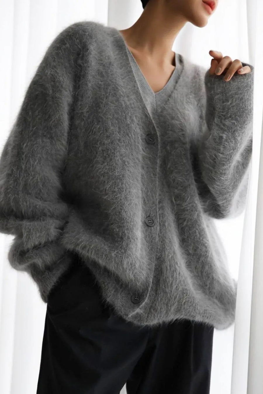 Person wearing a gray sweater against a white background