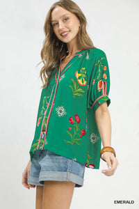 Woman wearing a green embroidered blouse with floral patterns on a white background