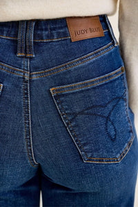Close-up of blue jeans with Judy Blue label on a plain background