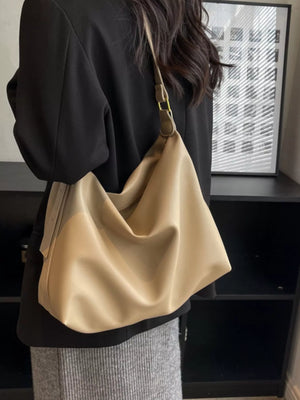 Person holding a beige handbag indoors