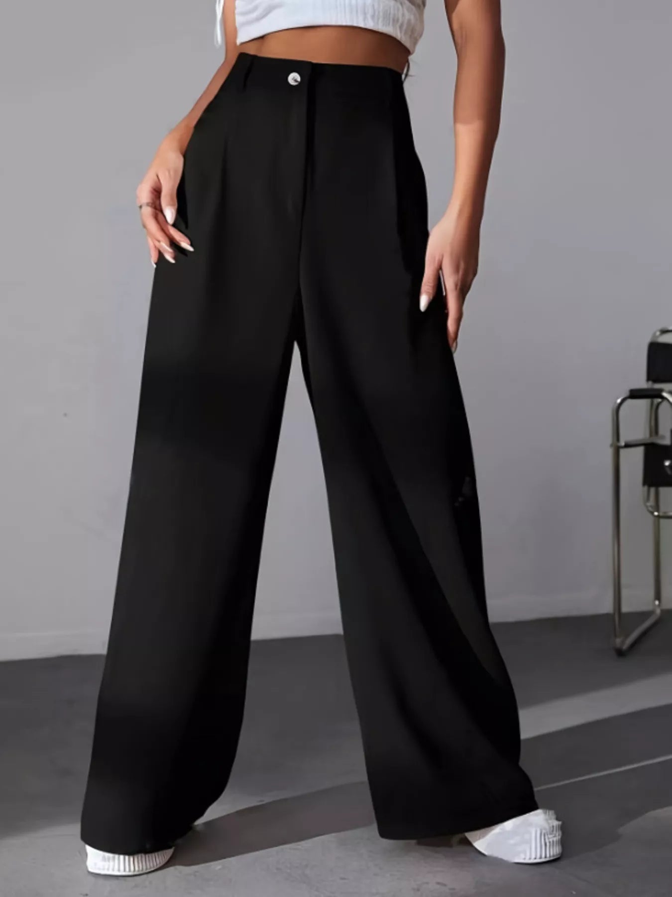 Person wearing black wide-leg pants on a gray background