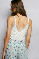 Woman wearing a white lace top and floral skirt against a plain background