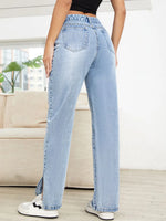 Person wearing light blue jeans in a room with a couch and plants.