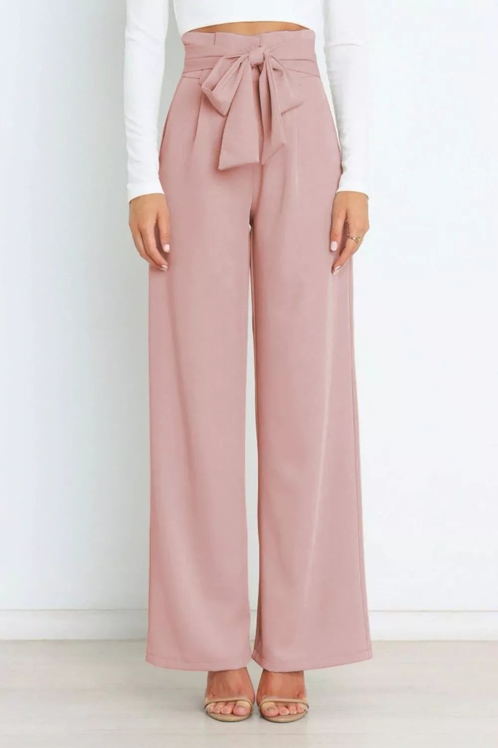 Pink wide-leg pants with a tie waist worn by a person on a white background