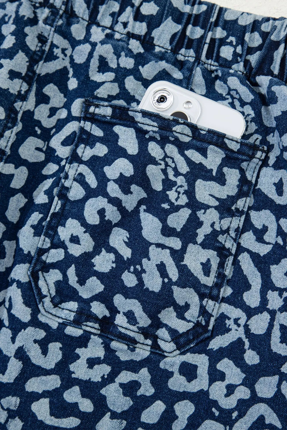 Navy blue shorts with a light blue leopard print pattern, showing a pocket.