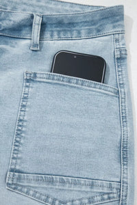 Light blue denim jeans with a smartphone in the pocket on a white background