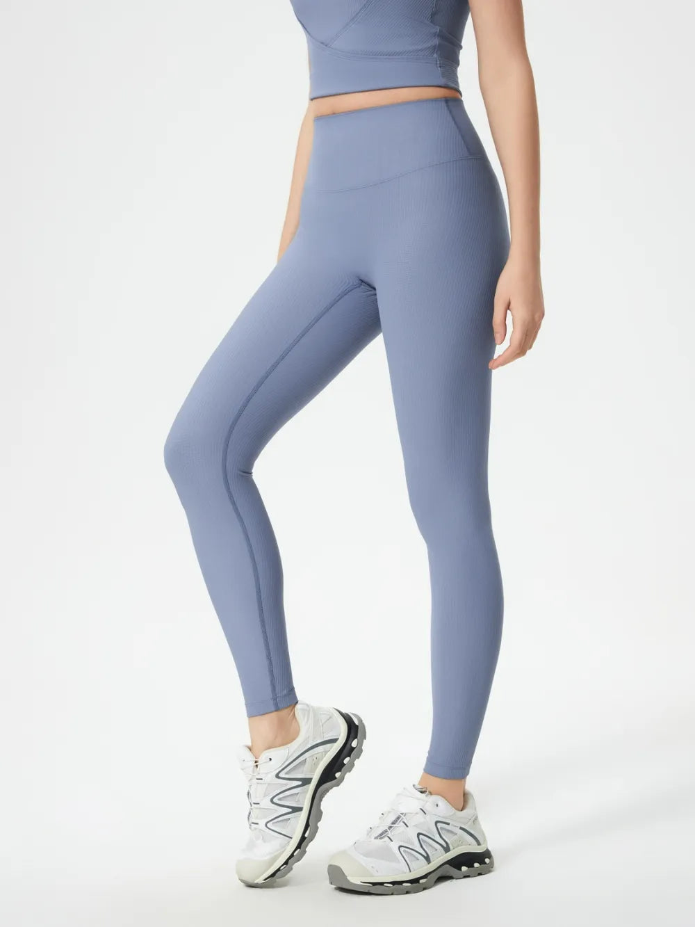 Person wearing blue leggings and white sneakers on a white background