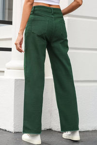 Green pants worn by a person standing against a white wall.