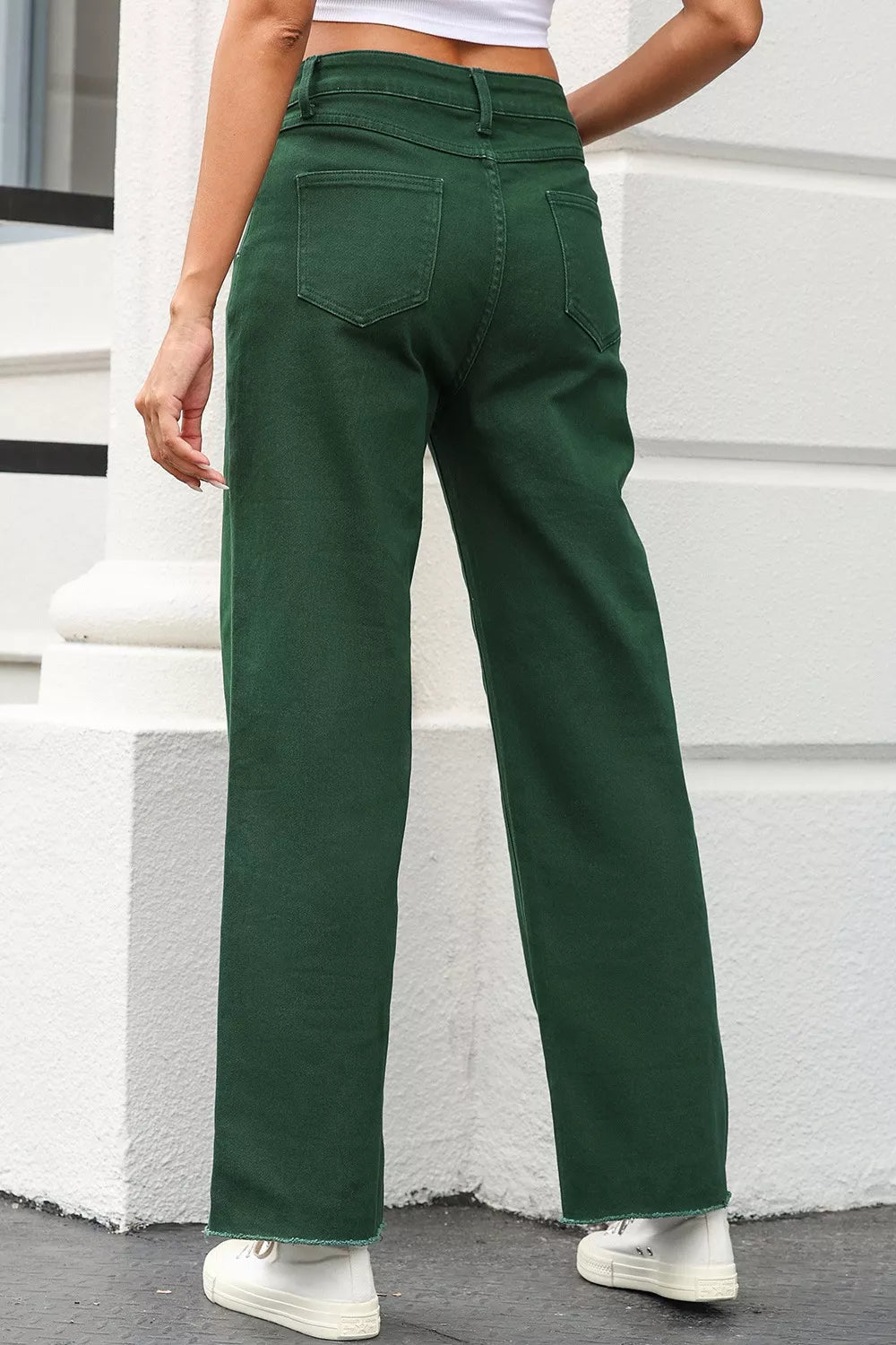 Green pants worn by a person standing against a white wall.