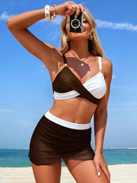 Woman in a brown and white bikini taking a selfie on a beach.