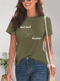Woman wearing a green t-shirt with text and graphic, standing against a neutral background.