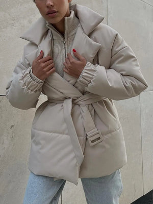 Person wearing a beige puffer coat against a neutral background