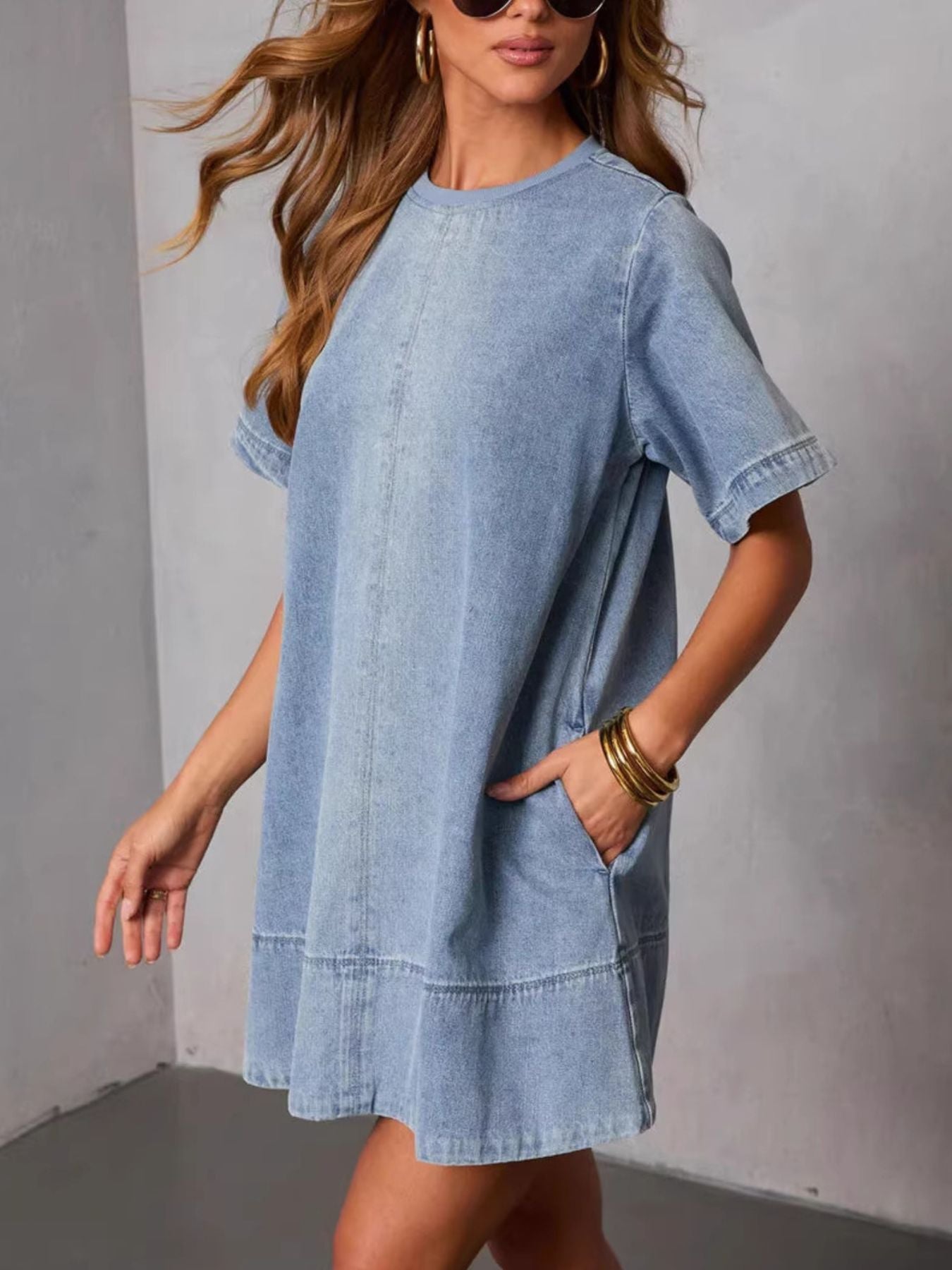 Woman wearing a light blue denim dress against a plain background
