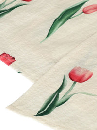 Close-up of a fabric with red tulip flowers and green leaves on a beige background