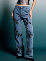 Blue jeans with black floral patterns worn by a person on a gradient background