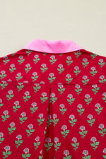 Red garment with floral pattern and pink collar on a beige background