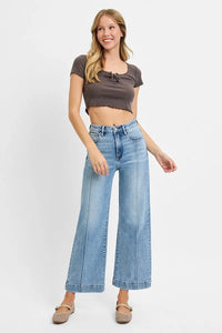 Woman wearing a brown crop top and blue jeans on a white background