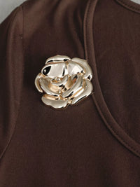 Gold rose brooch on a brown garment