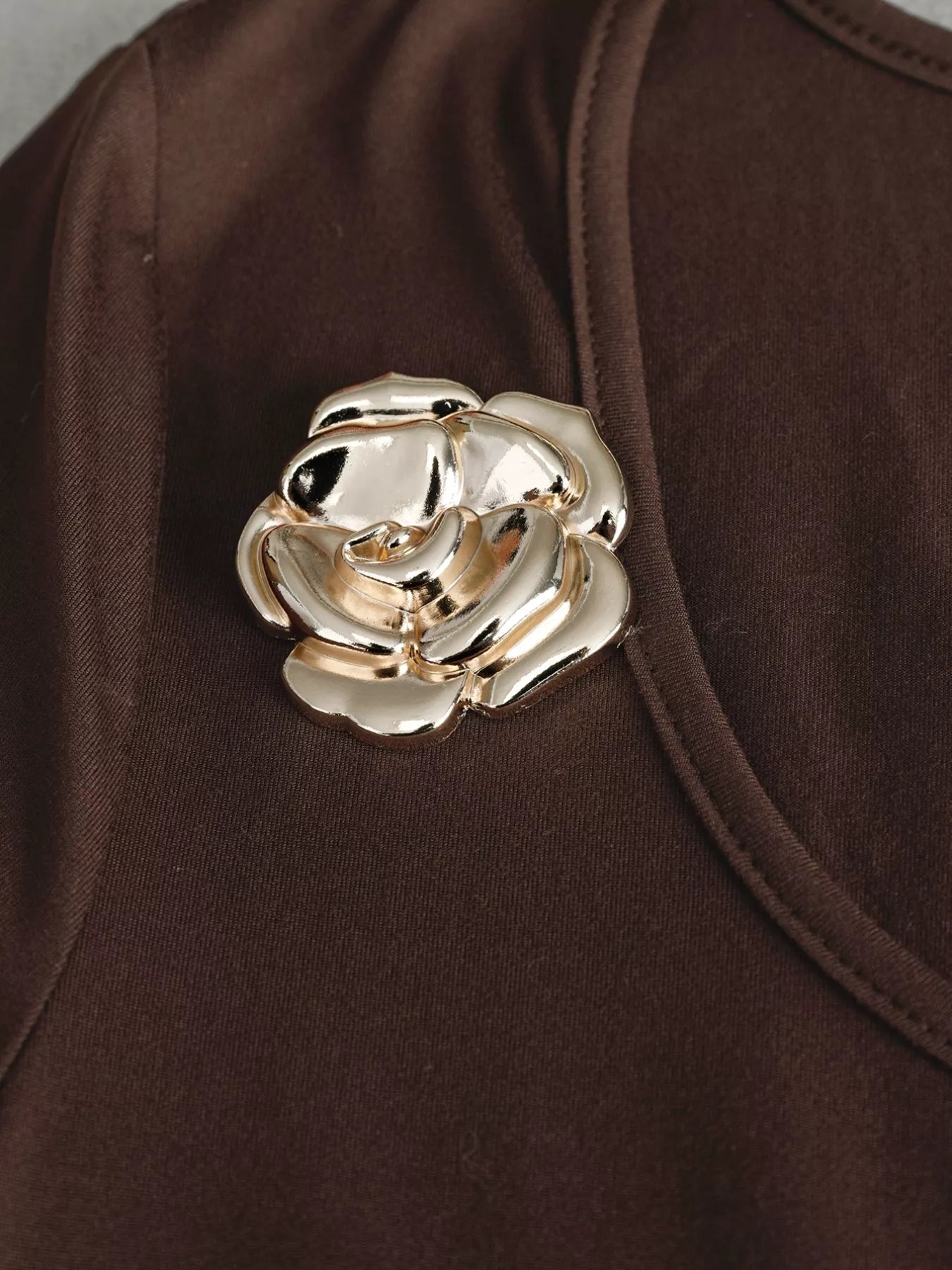 Gold rose brooch on a brown garment