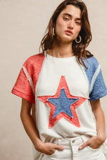 Woman wearing a white t-shirt with a red and blue star design on a beige background
