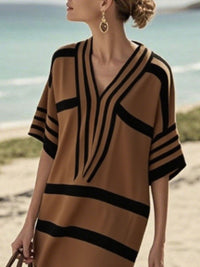 Woman wearing a brown and black striped dress on a beach.