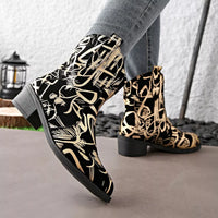 Black and gold patterned boots worn with gray pants on a neutral background