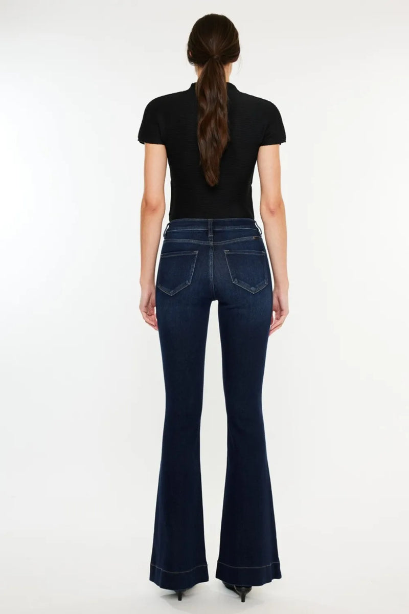 Person wearing dark blue flared jeans on a white background