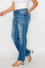 Person wearing blue jeans and a white top on a plain background